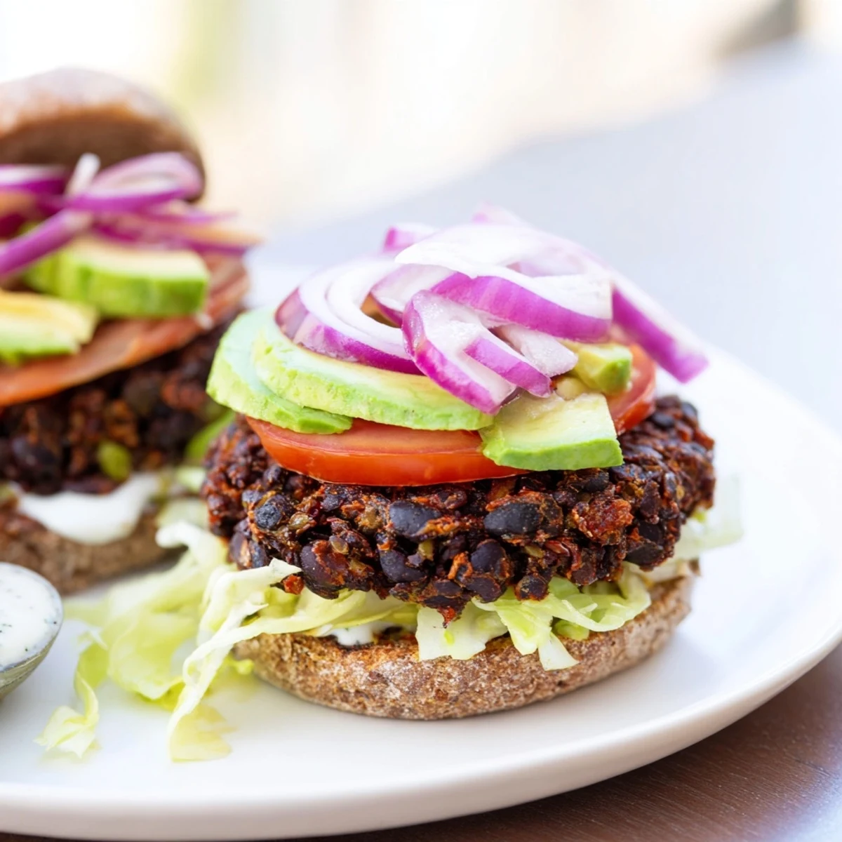 Close-up of a zesty black bean burger with fresh avocado, ready to be devoured with lime wedges.