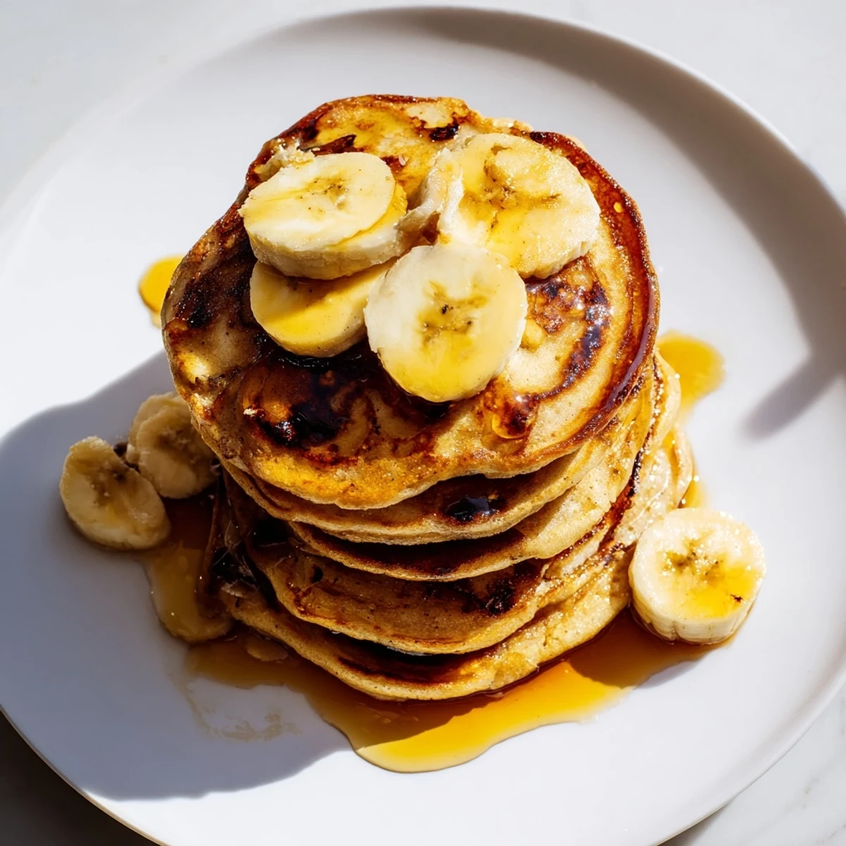 Fluffy Weekend Golden-Brunch Banana Pancakes, drizzled with warm maple syrup, perfect for a cozy brunch.