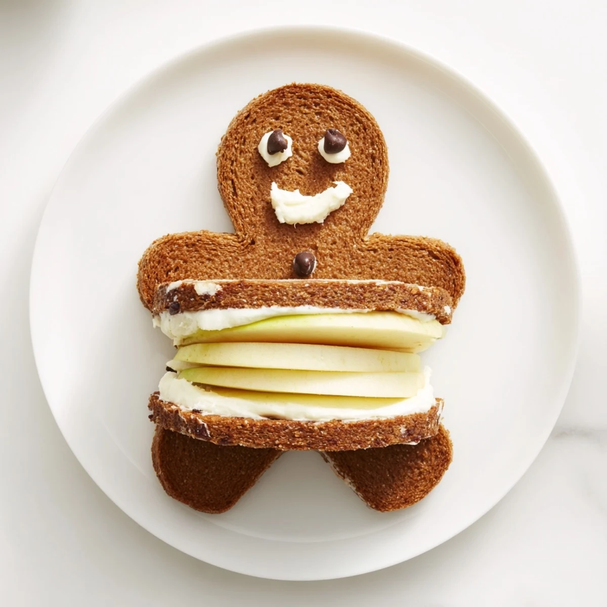 Golden gingerbread man sandwich cutouts with fruit faces and sweet cream filling, a cheerful lunch treat.
