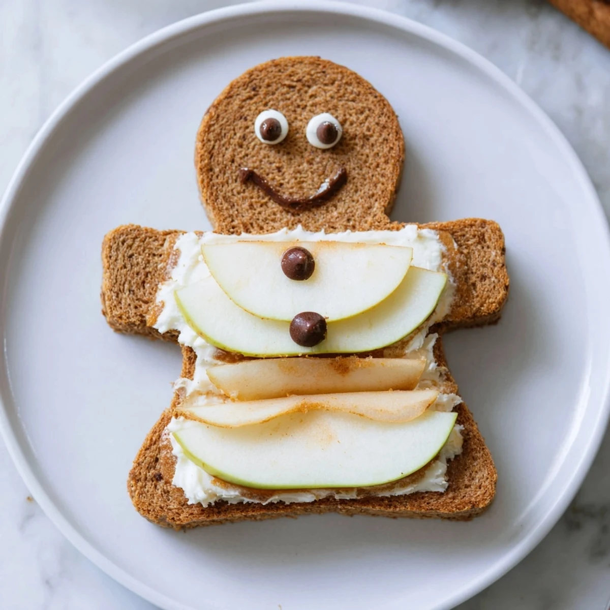 Colorful gingerbread man sandwich cutouts made with honey-sweetened cream cheese and sliced fruit.