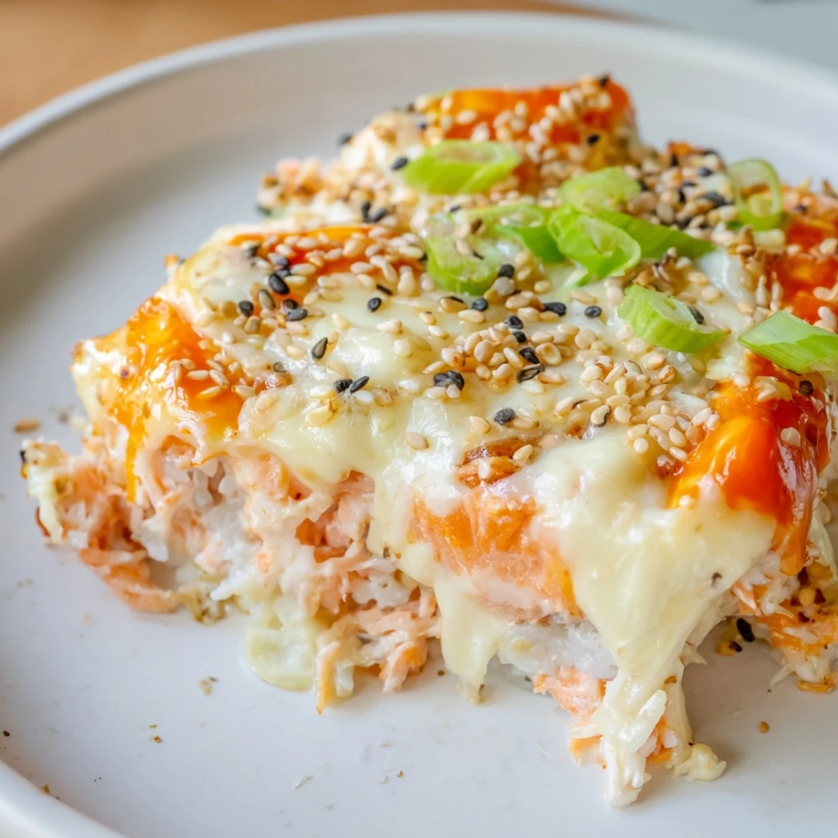 Deconstructed Creamy Salmon Sushi Bake: a close-up of the bubbly, golden cheese crust and flaked salmon.