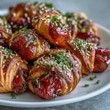 Freshly baked Pepper Jelly Hogs in a Blanket garnished with chives and sesame seeds for a party.