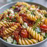 Colorful picnic pasta salad with Italian dressing, vibrant veggies, and mozzarella pearls in a large bowl.