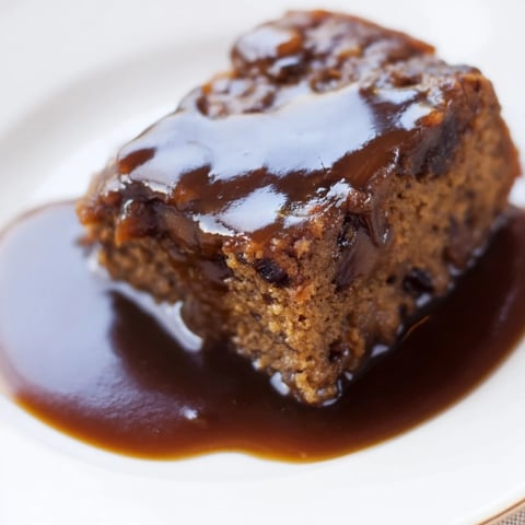 Warm, inviting photo of Weekend Cabin-Style Sticky Toffee Pudding drizzled with shimmering toffee sauce.