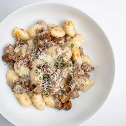 A close-up shot of Woodsy Skillet Sausage and Mushroom Gnocchi, ready to serve with creamy sauce.