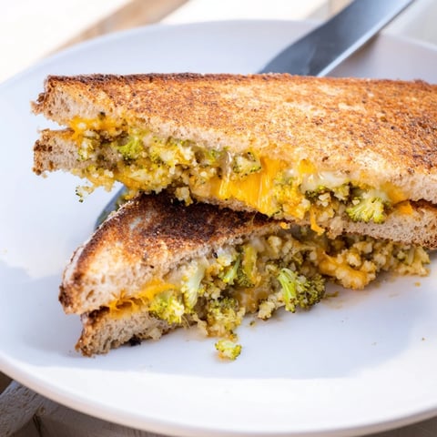 Golden toasted sourdough slices hold melted sharp cheddar and tender, caramelized roasted broccoli in this hearty Roasted Broccoli & Cheddar Grilled Cheese sandwich.