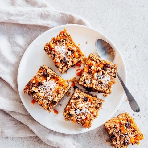 A warm slice of Carrot Cake Baked Oatmeal topped with maple syrup and chopped walnuts on a rustic plate.