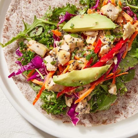 Freshly-made Poppy-Inspired Chicken Salad Wraps: a close-up of colorful filling spilling over.