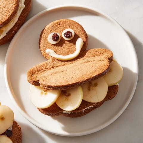 Playful gingerbread man sandwich cutouts, beautifully arranged with apple smiles, perfect for a kids' party.