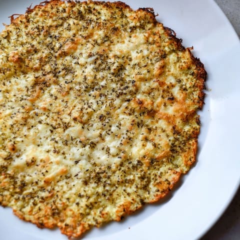 Oven-baked cauliflower pizza crust, lightly browned, perfect base for your favorite flavors.