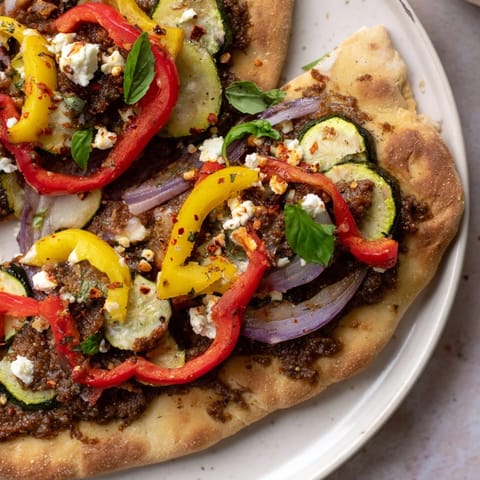 Savor the flavors of this vibrant naan bread pizza with tangy olive tapenade and fresh herbs.