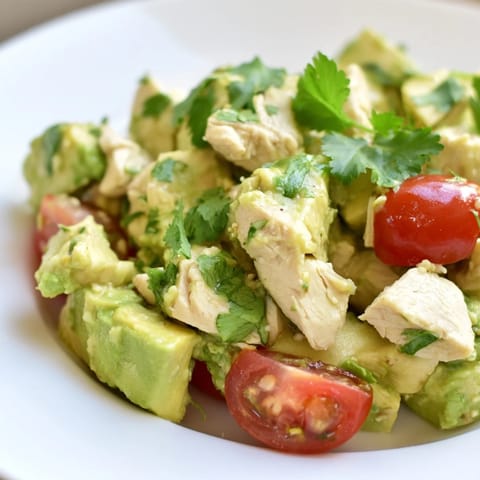 Fork-tender chicken and ripe avocado pieces tossed in a zesty lime dressing, topped with fresh cilantro and parsley for a healthy lunch.