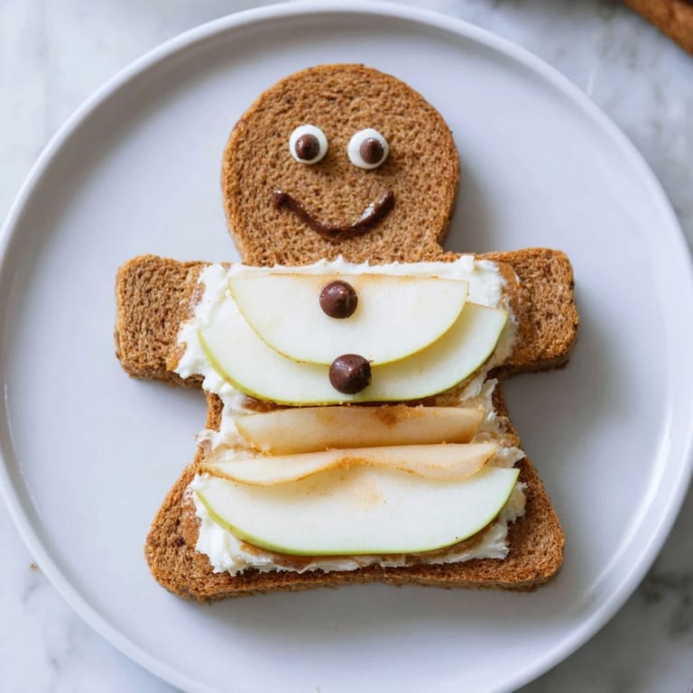 Colorful gingerbread man sandwich cutouts made with honey-sweetened cream cheese and sliced fruit.
