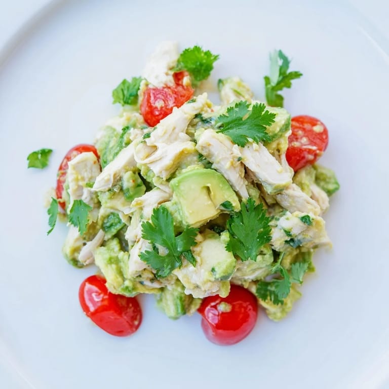 A close-up of fresh Avocado Chicken Salad featuring diced cucumbers, red onion, and cherry tomatoes, served in a light lettuce cup for a low-carb meal.