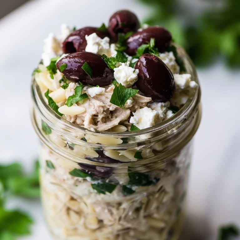 Bright meal prep jars featuring juicy grilled chicken, briny Kalamata olives, crumbled feta, and a tangy red wine vinegar dressing over orzo pasta.